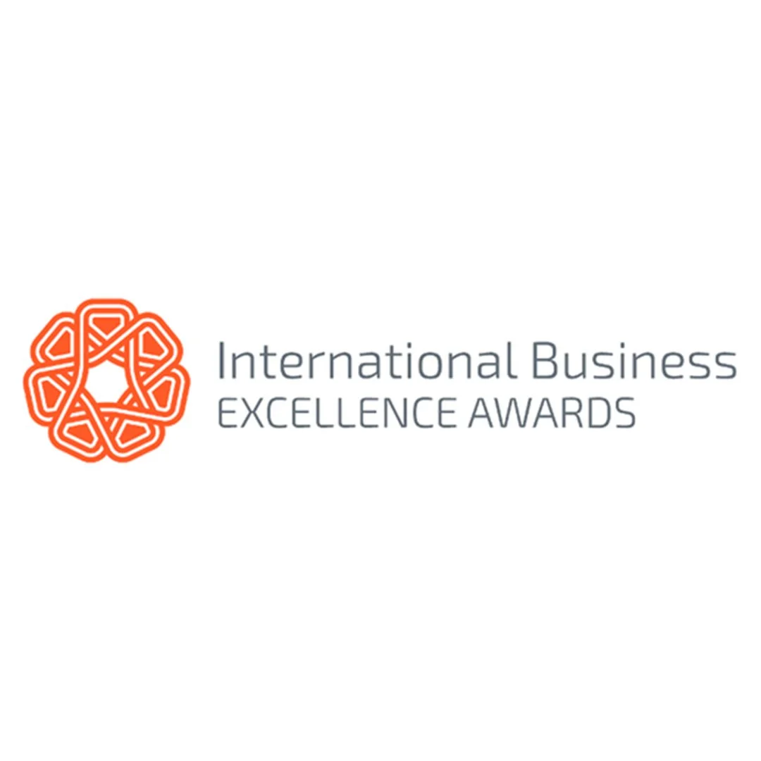 Logo for the International Business Excellence Awards, featuring an orange geometric emblem and the text in gray.