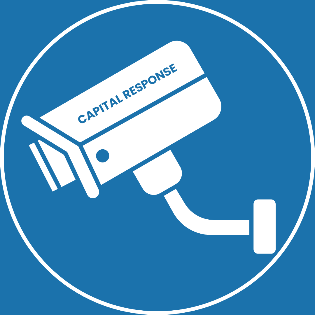Blue circular sign with a white security camera and the words 'CAPITAL RESPONSE' on the camera, indicating video surveillance and CCTV.