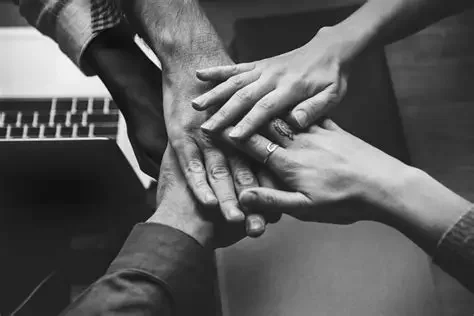 Multiple hands stacked together in a show of unity and teamwork.