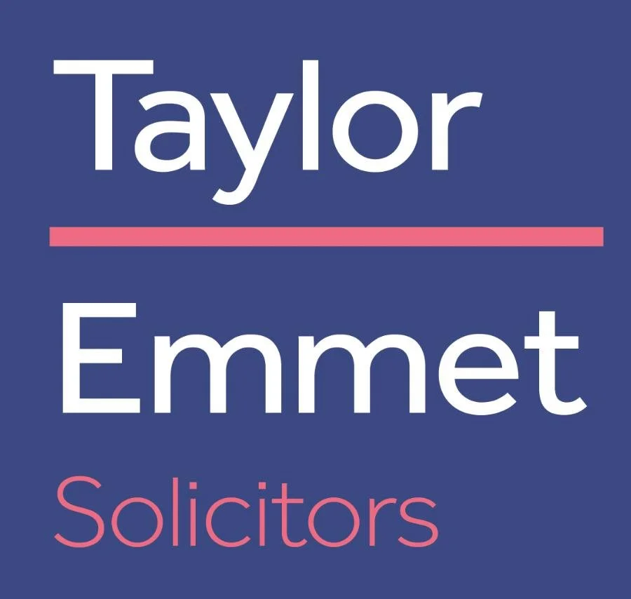 Political campaign sign with blue background, displaying the names 'Taylor Emmet' in large white letters and the word 'Solicitors' in pink at the bottom.