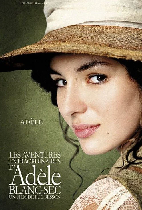 Close-up of Adele wearing a wide-brimmed straw hat and a lace top, with a soft smile, on a movie poster for her film 'Les Aventures Extraordinaires d'Adèle Blanc-Sec'.