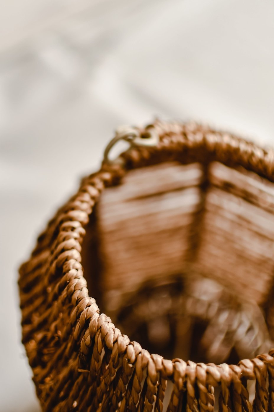 Close-up of a woven brown wicker basket or container, looking down into it, with a blurred background.