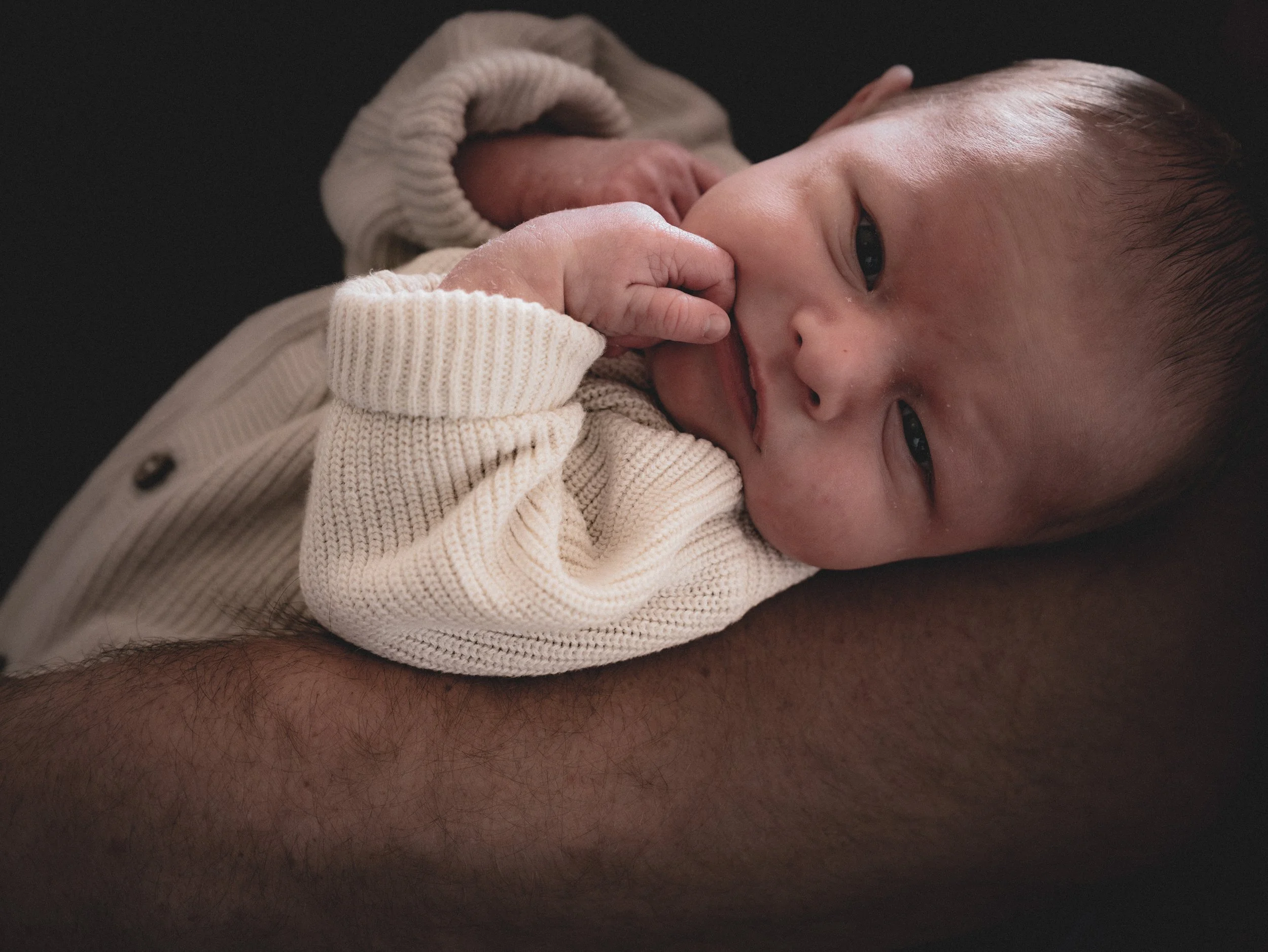 Een pasgeboren baby die op de arm ligt van mama of papa.