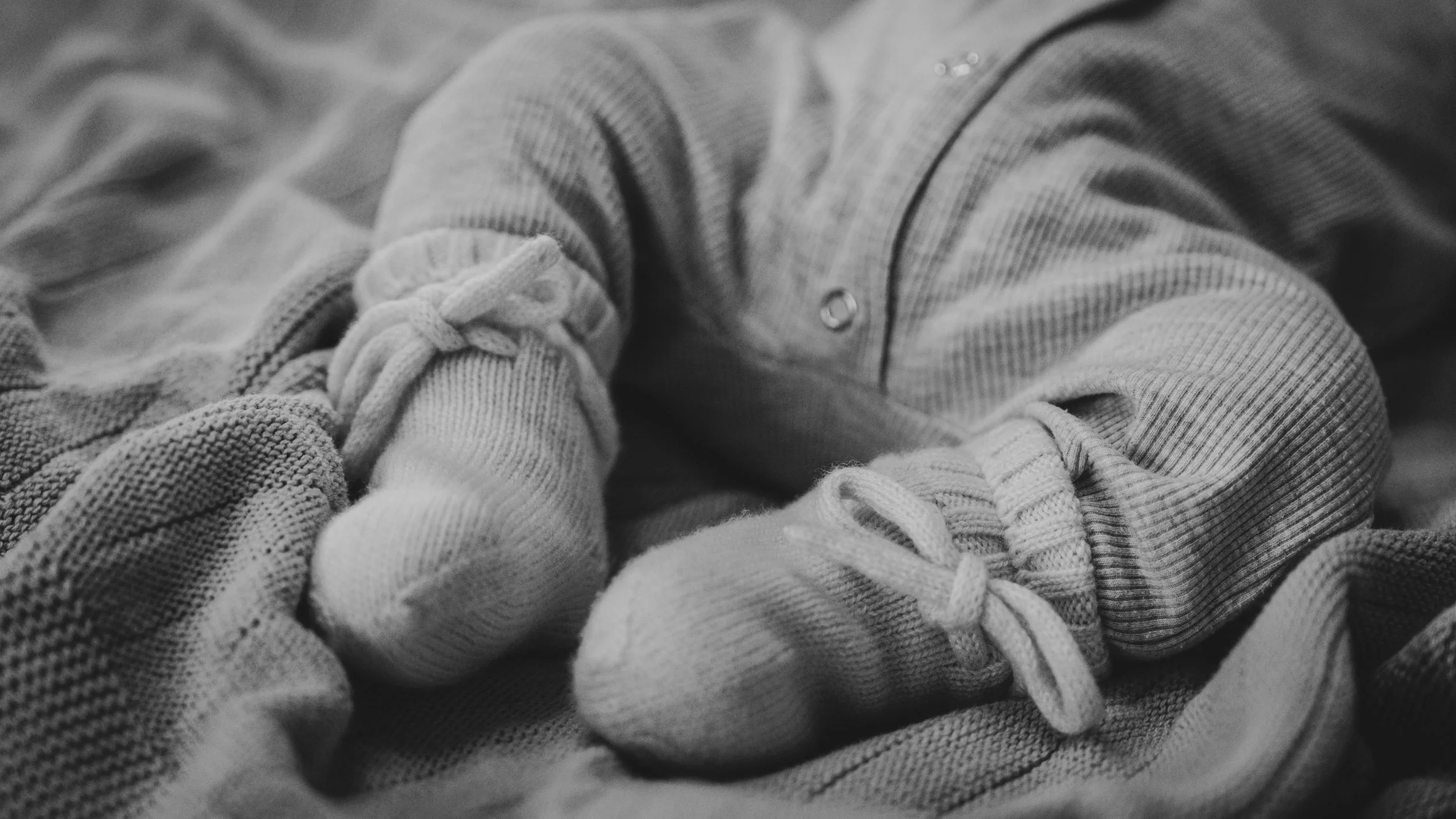 Close-up van babyvoetjes in sokken op een bed.