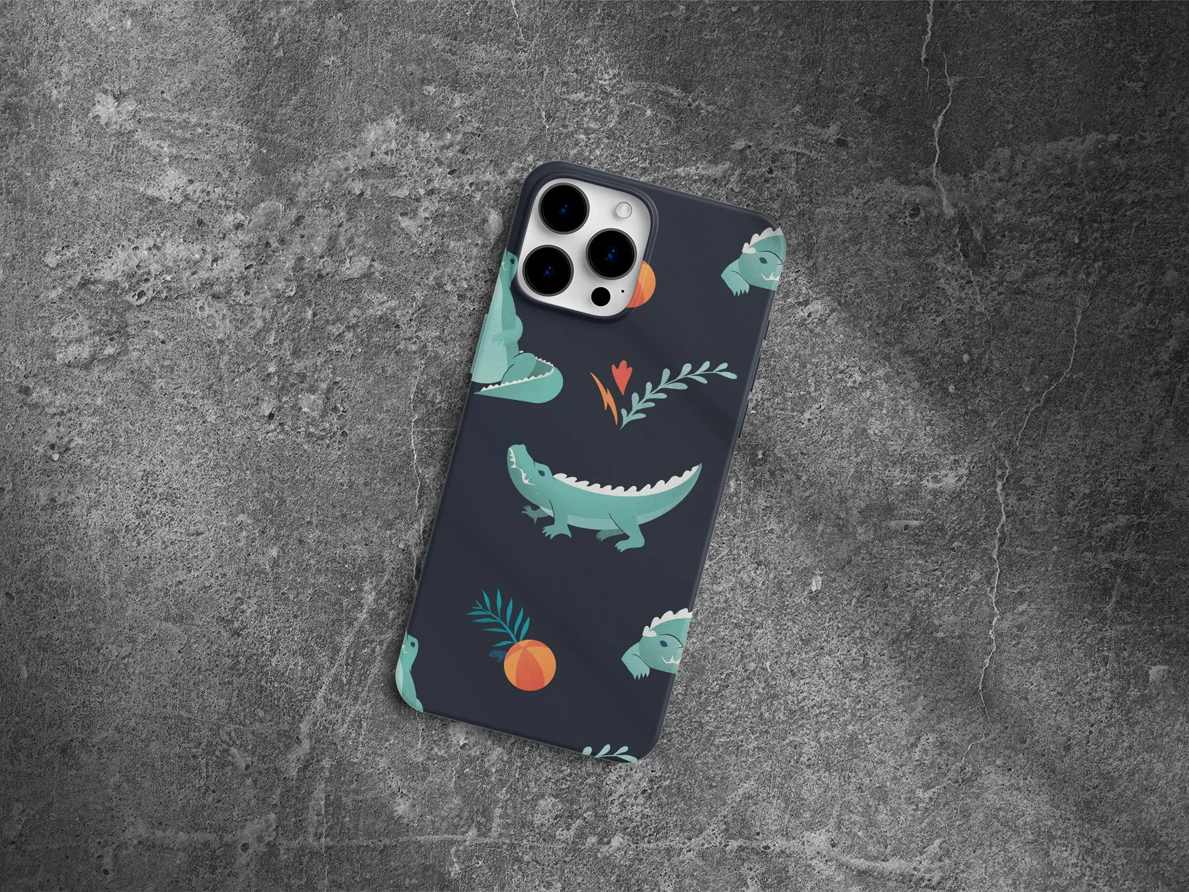 A smartphone with a dark blue case featuring a pattern of alligators, peaches, and leaves, lying on a textured dark gray surface.