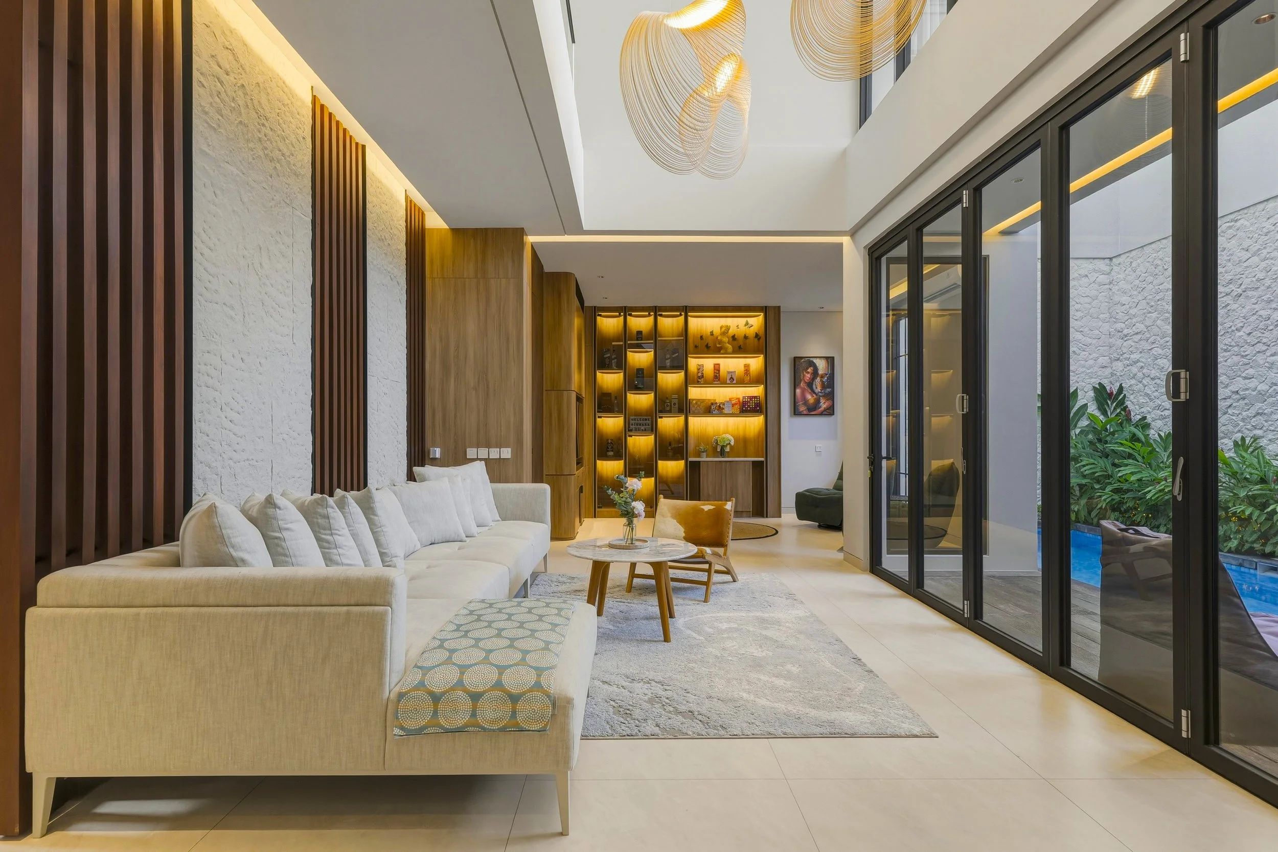Modern living room at Juwana Villa Residence in Sanur, Bali, featuring warm wood interiors, comfortable seating, and contemporary tropical design.