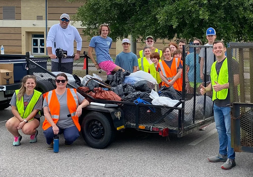 A group of volunteers pose with a trailer full of trash that they collected during a previous county wide clean up event.