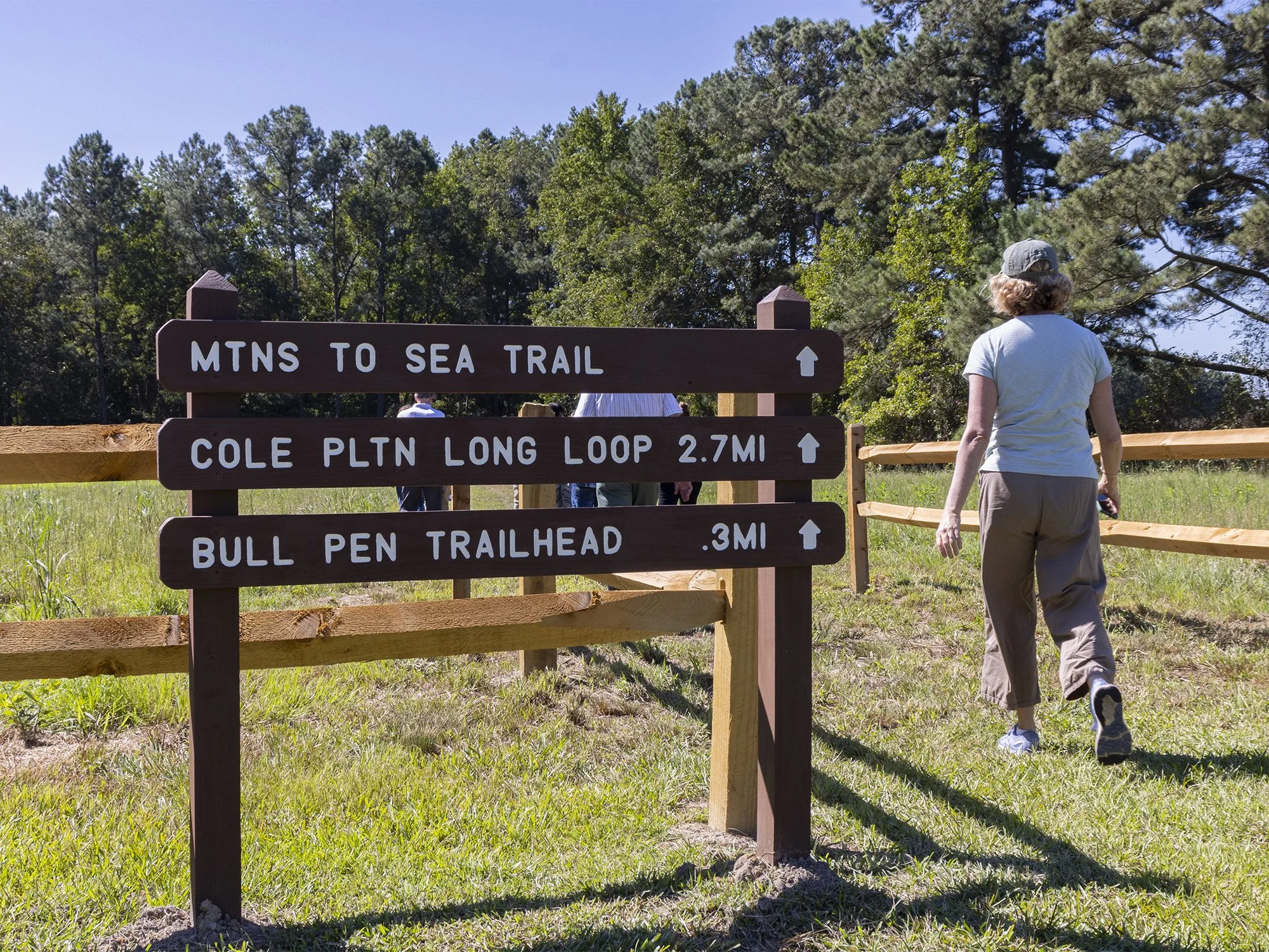 Hikers entering a trail at Bentonville Battlefield with the trailhead sign visible.
