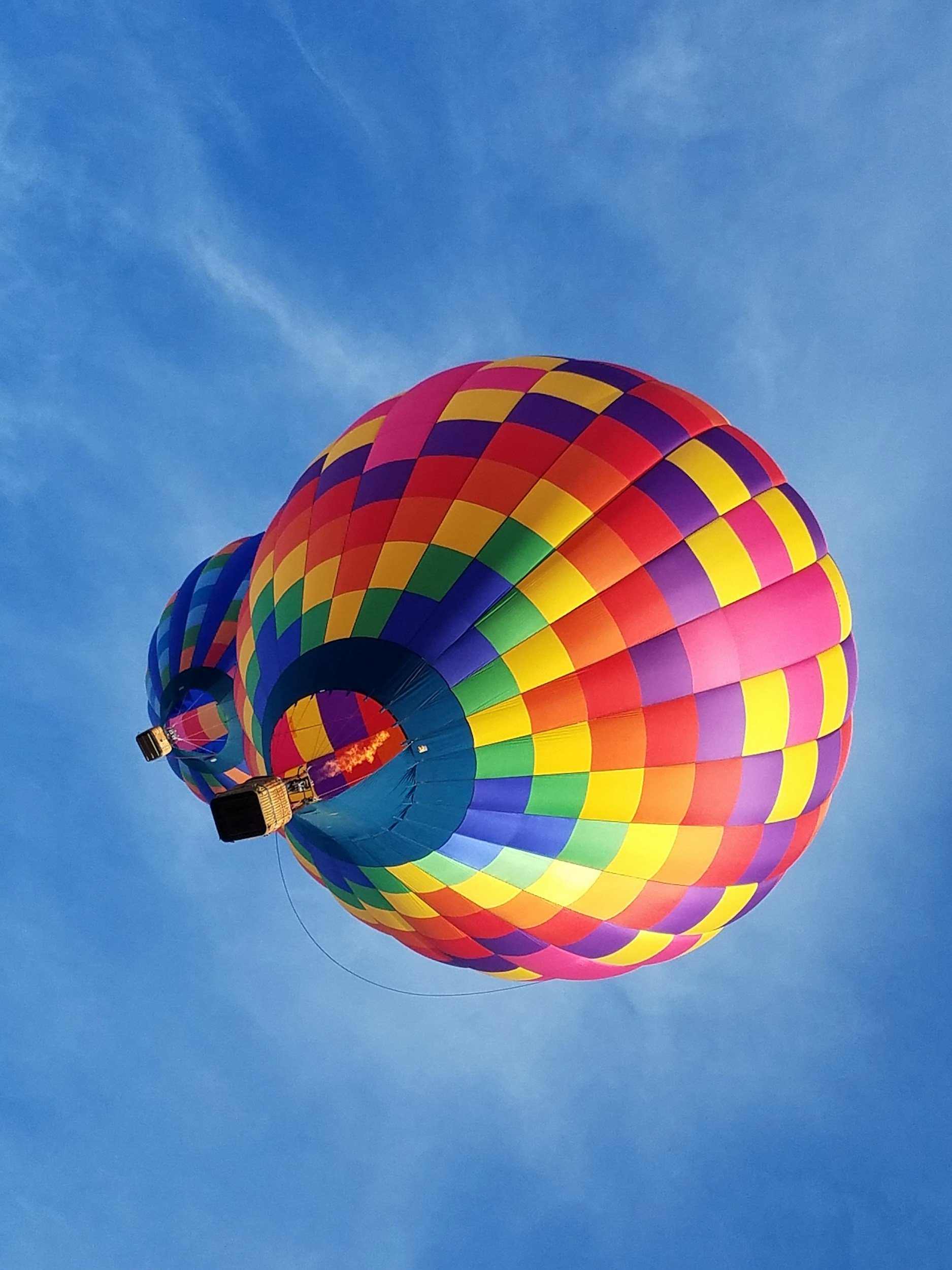 Colorful hot air balloon flying in a clear blue sky.