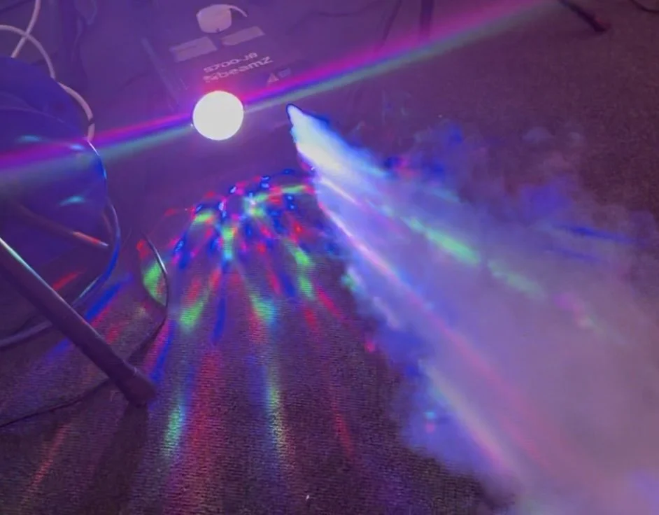 Colorful laser lights are projected onto a carpeted floor, creating vibrant patterns of red, green, and blue.