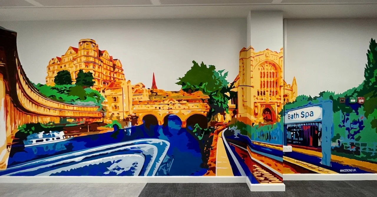 Colorful mural of a cityscape with historic buildings, a river, and a bridge, featuring a train station labeled Bath Spa.