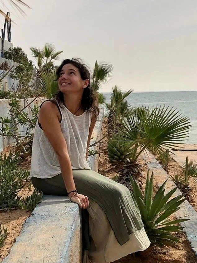 Coach en développement personnel assise dans un environnement naturel, souriante et bienveillante, symbolisant l’espoir et le mieux-être