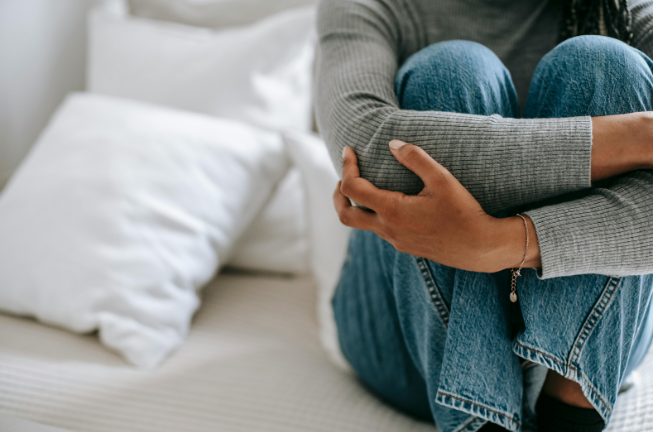 Adolescent assis en boule sur son lit, se tenant les genoux, illustrant le repli sur soi et les difficultés émotionnelles