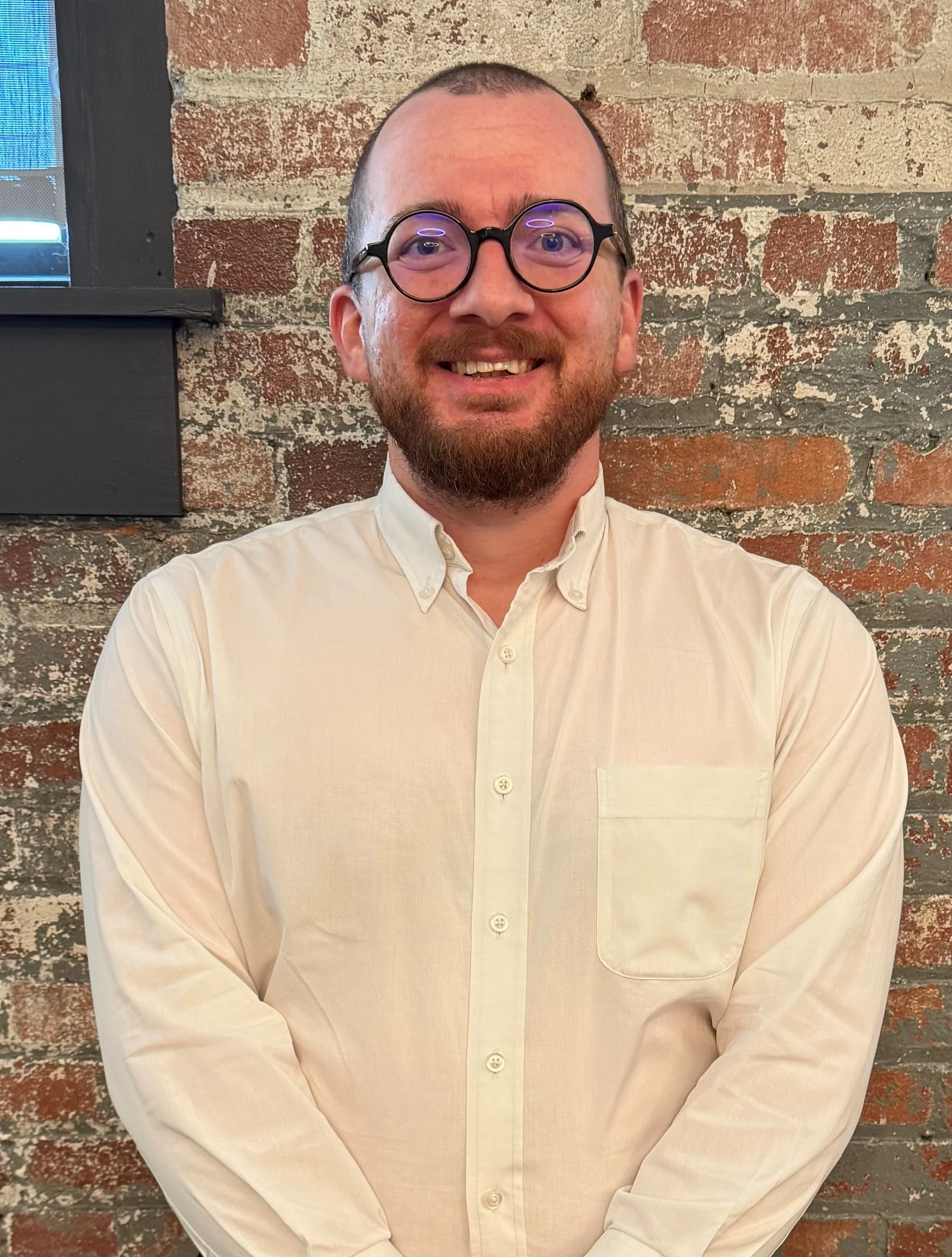 A man in a white shirt against a brick background