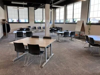 Empty modern conference room with tables, chairs, large windows, and a whiteboard