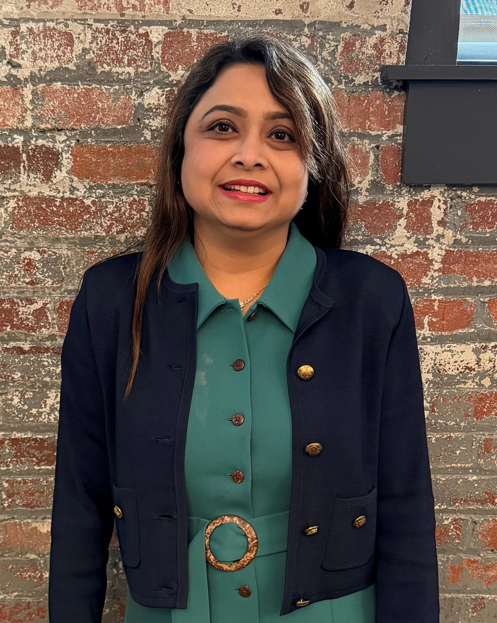 Picture of a woman in a suit jacket against a brick background