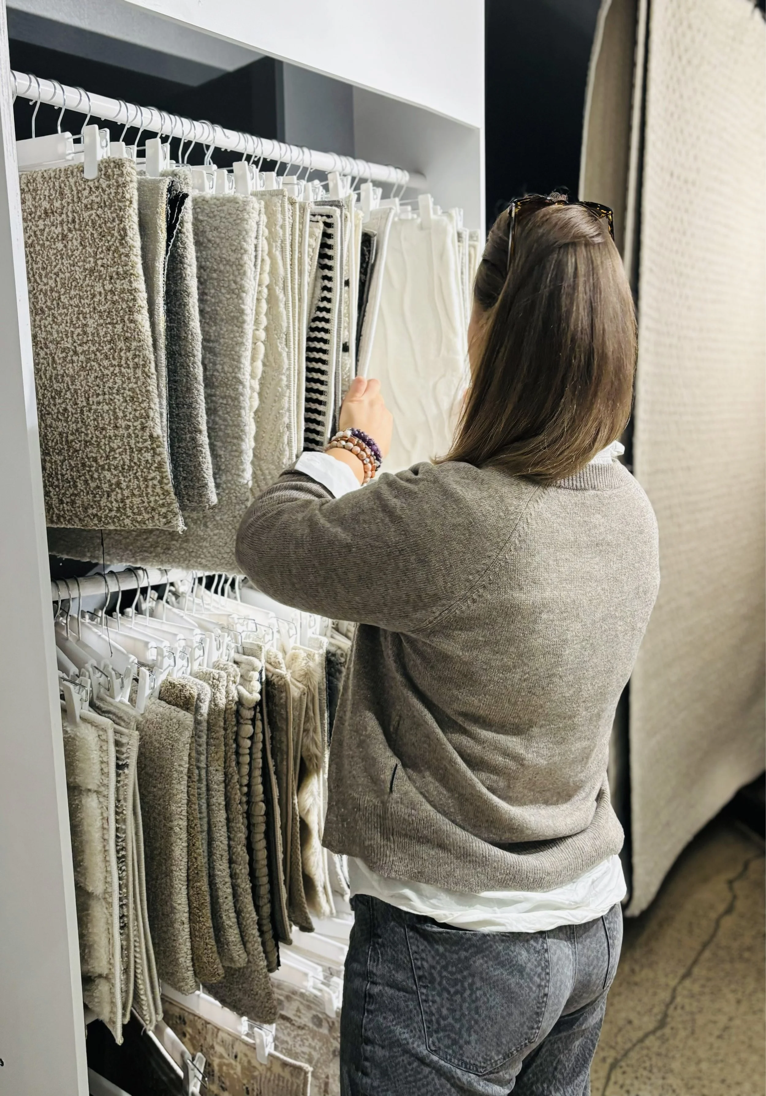 Une femme regarde un échantillon de tissus dans un magasin de décoration intérieure.