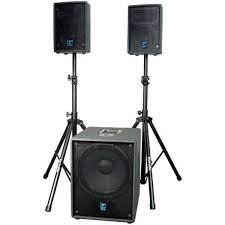 Two black speakers on stands and a large subwoofer in front, all set up for audio playback.