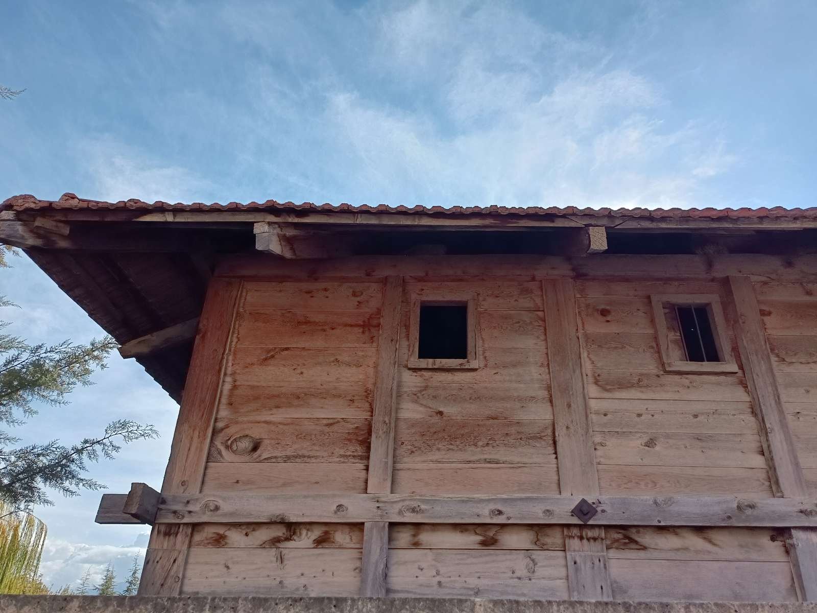 Ahşap bir ev, iki küçük pencere ve kırık bir çatı.