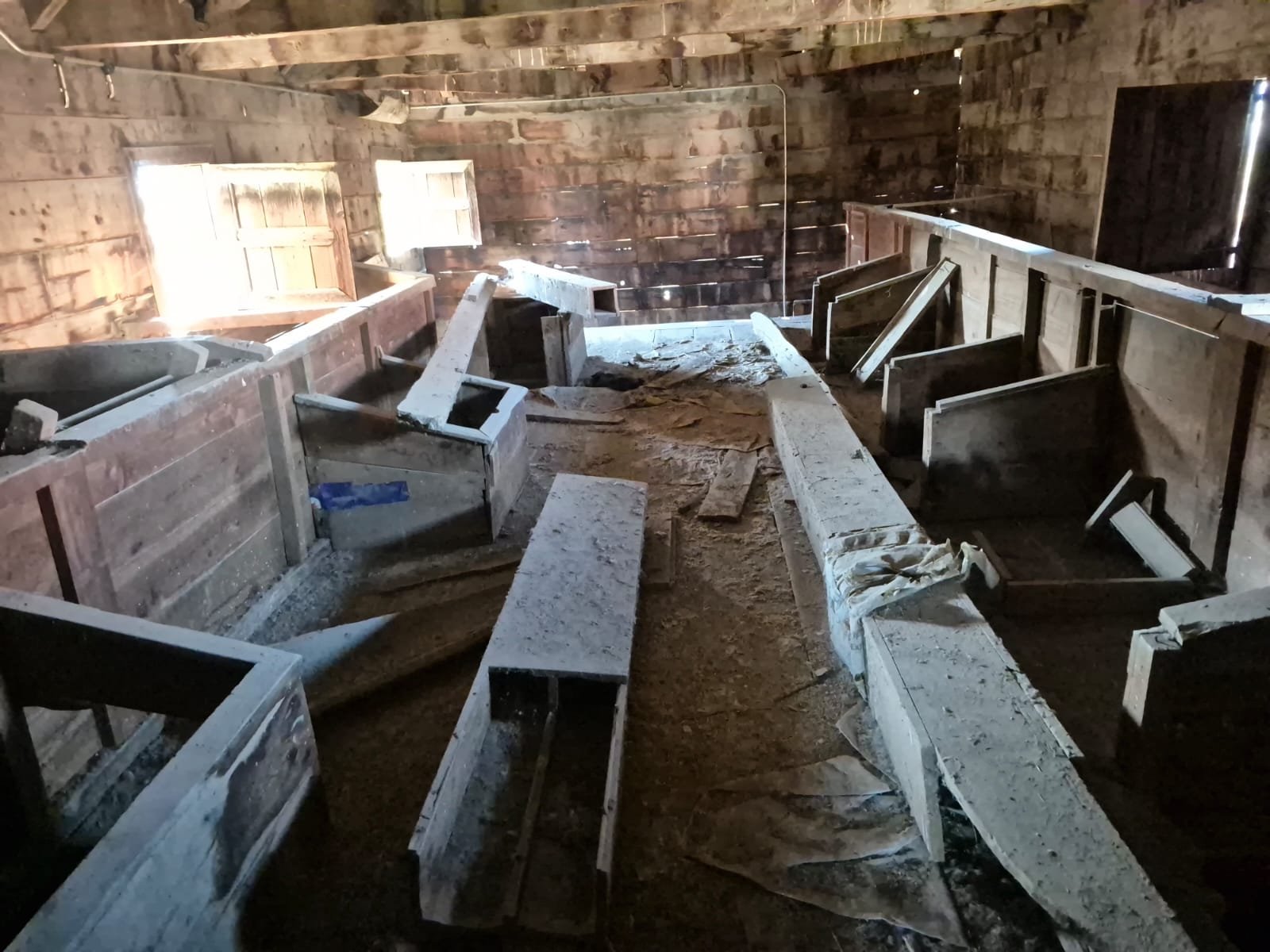 Kırık ve eski ahşap mobilyalar ve yapılar, ahşap duvarlar, pencereler ve toprak zemin ile eski, kullanılmayan veya terkedilmiş bir iç mekan. 