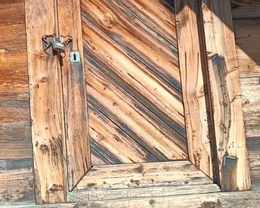 Ahşap kapı ve ahşap duvar. Kapı kanatları ahşap plakalarla çapraz düzenlenmiş.