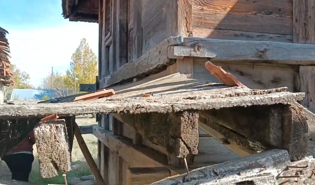 Ahşap bir yapının dış kenarındaki ahşap ve tuğla parçaları, eski ve zarar görmüş.