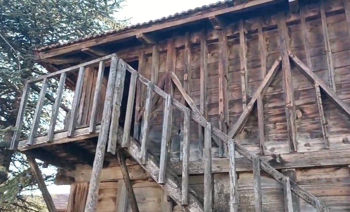 Ahşap bir evin dış cephesi, ahşap merdiven ve korkuluklar.