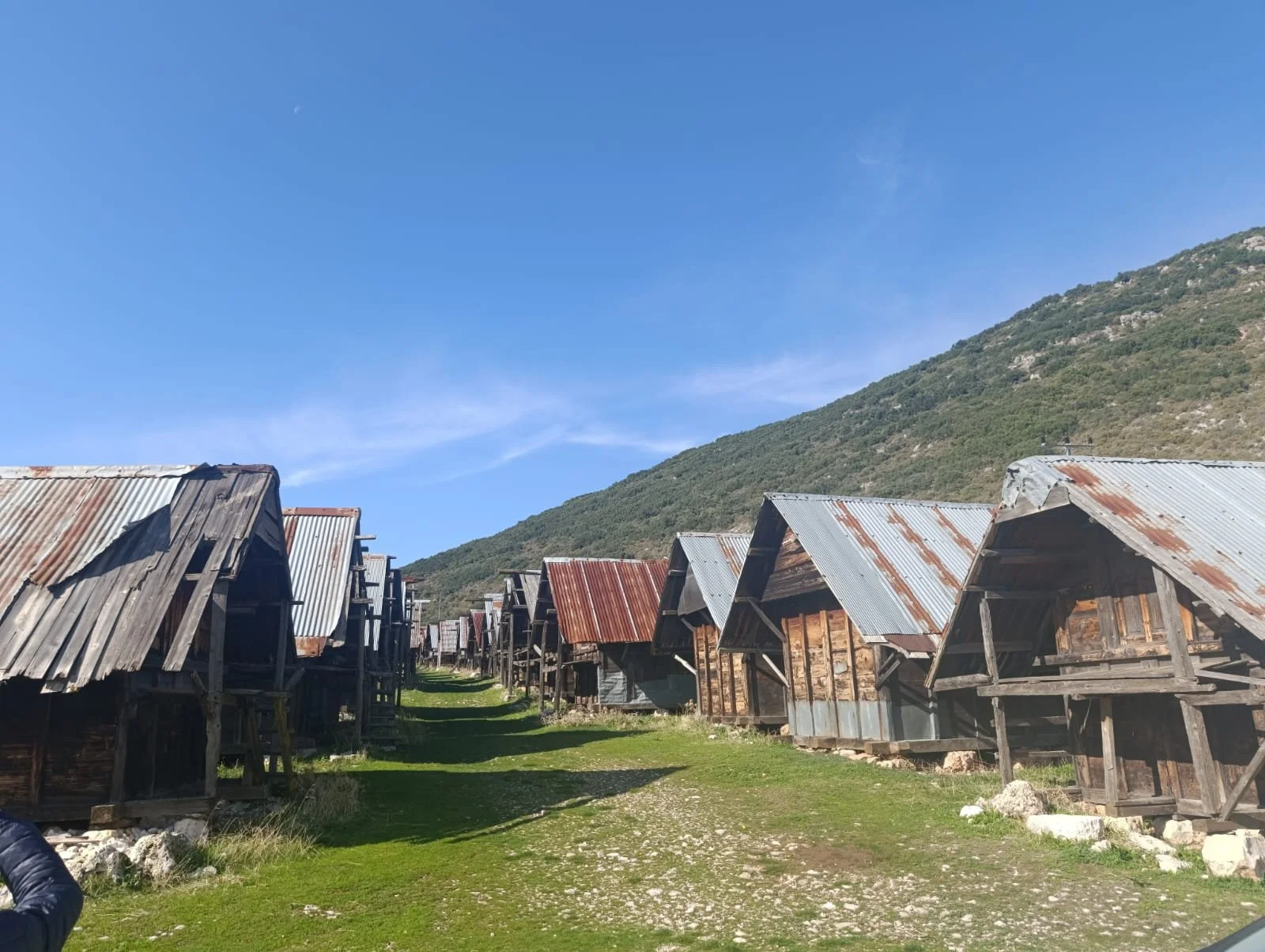 Dağ manzaralı, ahşap ve metal çatıya sahip eski kulübeler sıralanmış