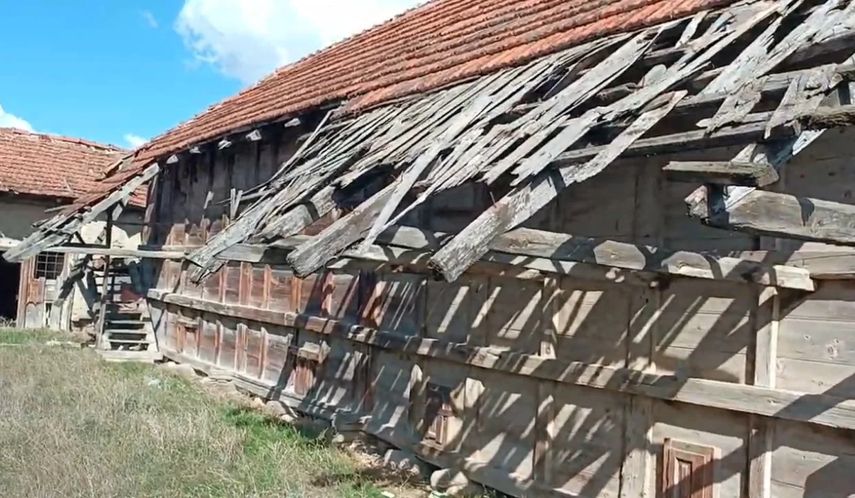 Eski, ahşap ve kırık bir evin çatısı, gökyüzü ve bulutlar görünmekte.