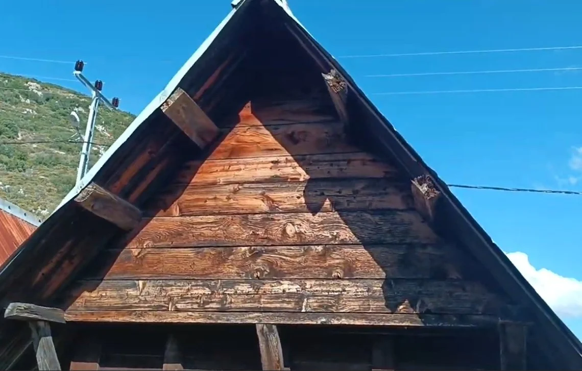 Ahşap bir çatının köşesinden gökyüzü ve elektrik direği görünmektedir.