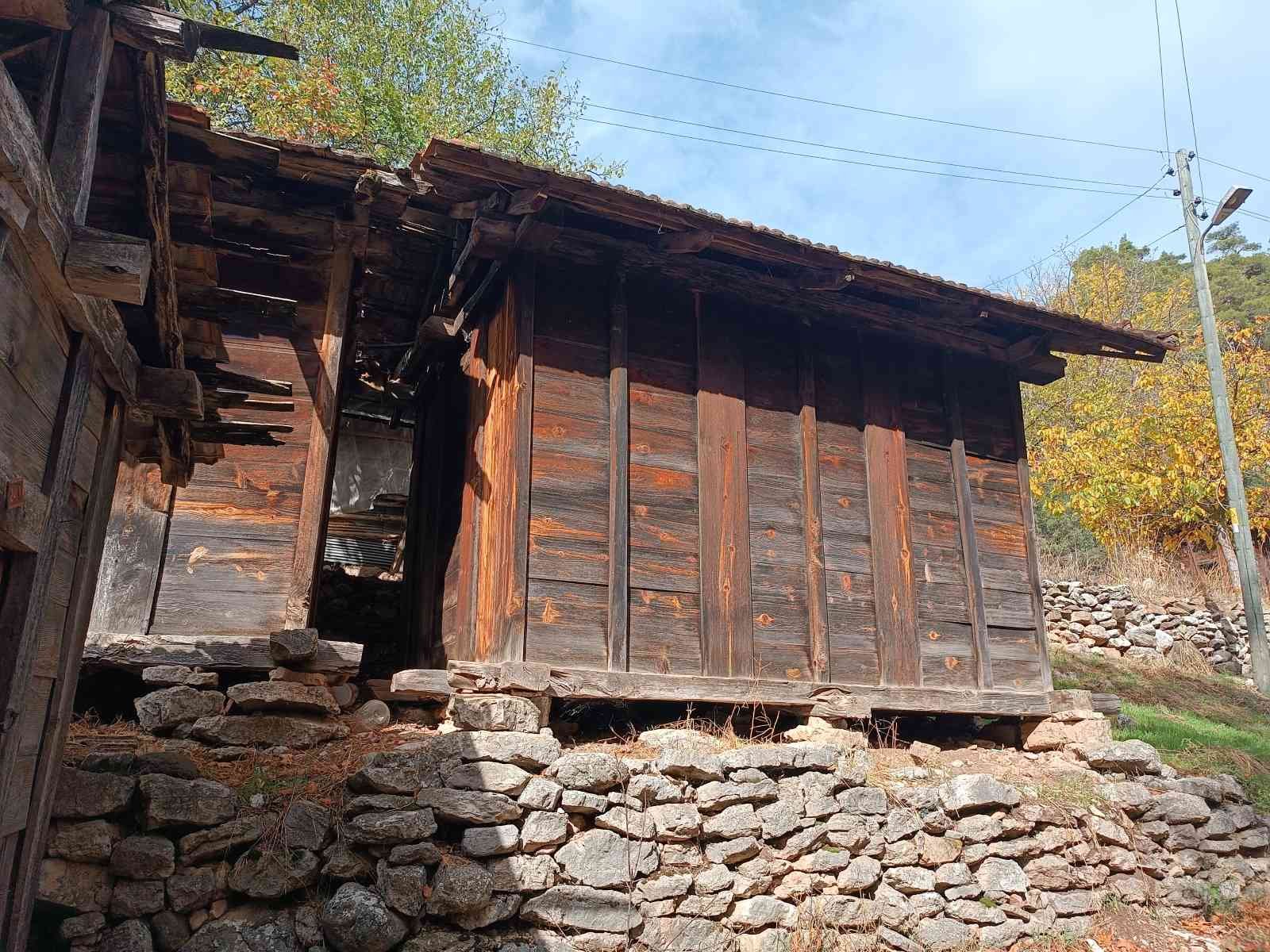 Ahşap ve taş yapılı eski bir ev, yerden biraz yükseltilmiş, arka planda ağaçlar ve elektrik direği var.