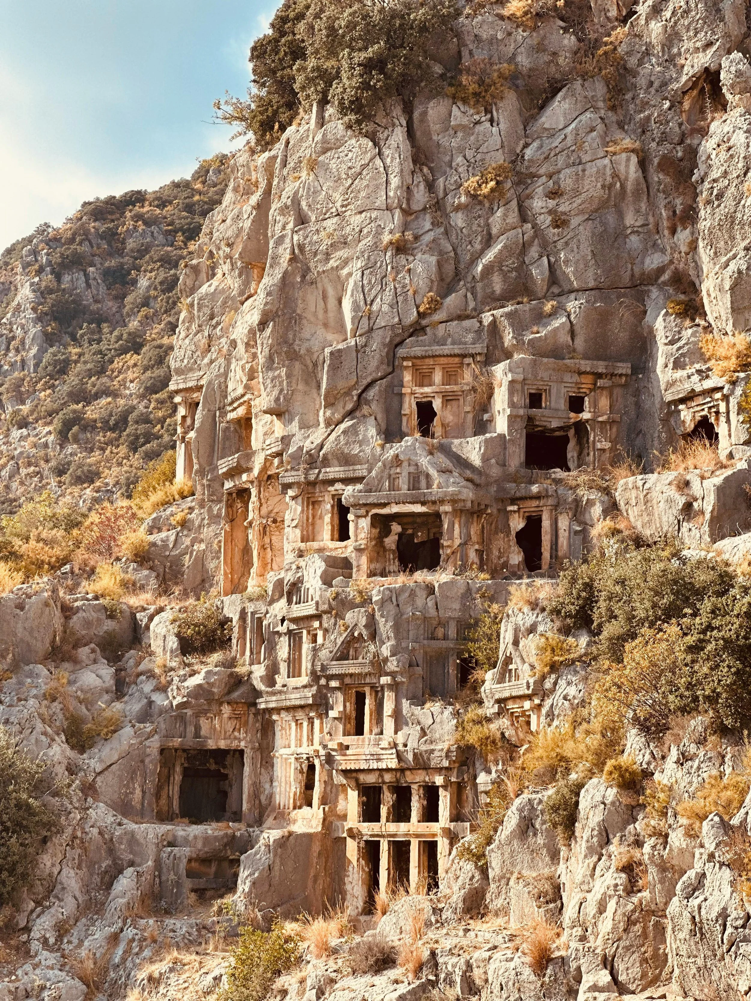 Kayalara oyulmuş antik Likya mezarları veya yapıları, dağlık bir alanda yer alıyor.