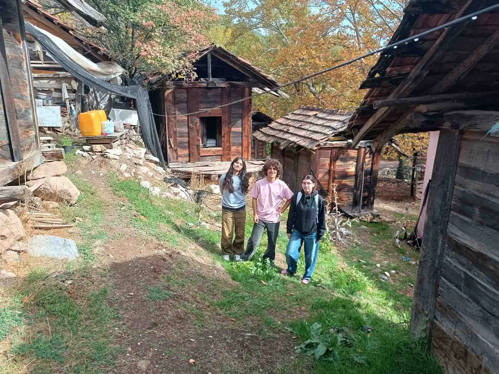 İlkbahar sonu veya sonbahar başında, ağaçlar renk değiştiriyor. Üç genç kadın ve erkek, ahşap evlerin yakınında, yeşil çimenli patikada duruyor.