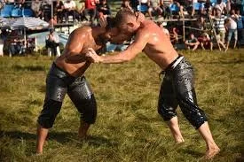 İki erkek güreşçi açık havada güreşiyor.