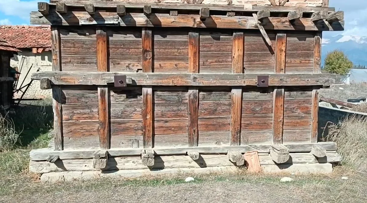 Ahşaptan yapılmış eski bir yapı veya çerçeve, açık alanda duruyor.