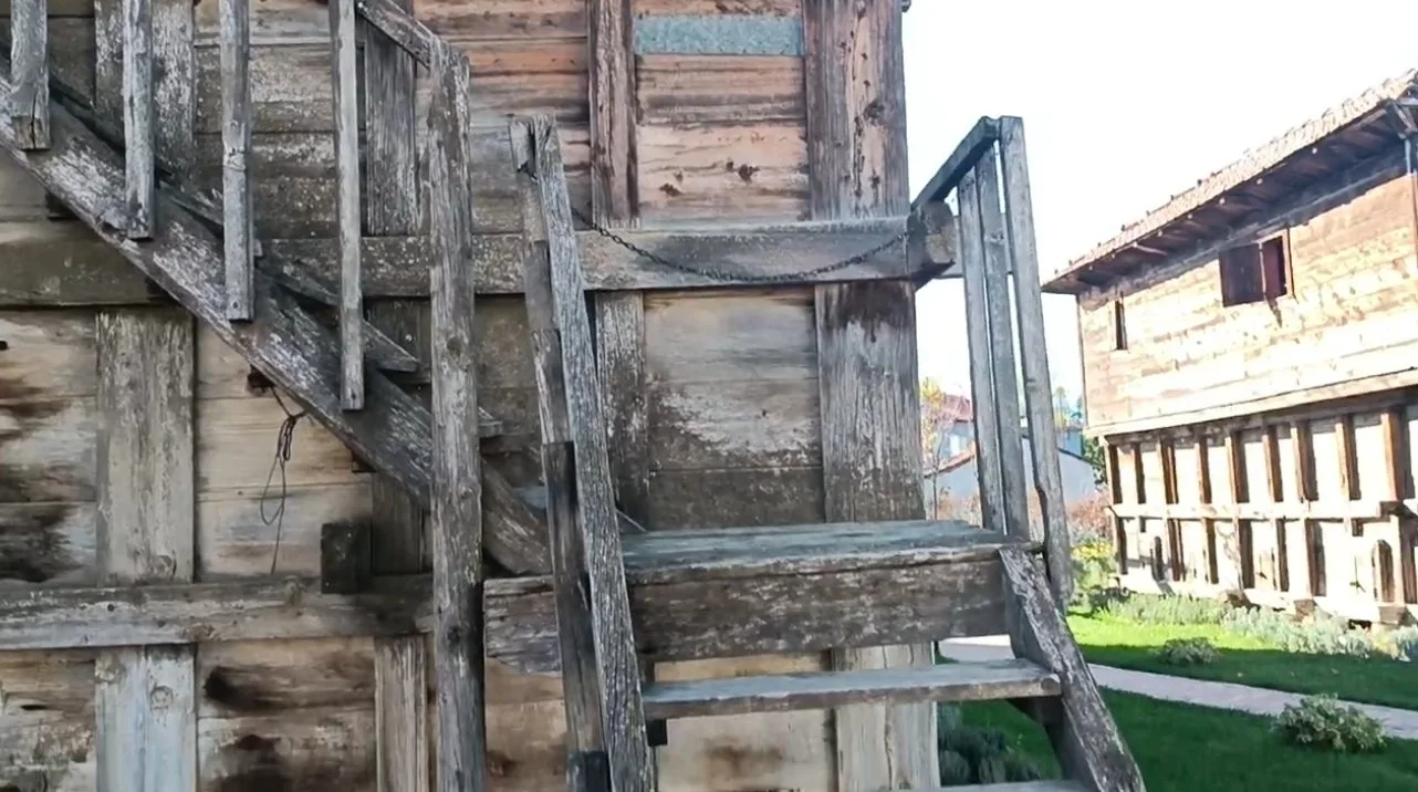 Ahşap merdiven ve bina duvarları, eski ve bakımsız durumda, dış mekan