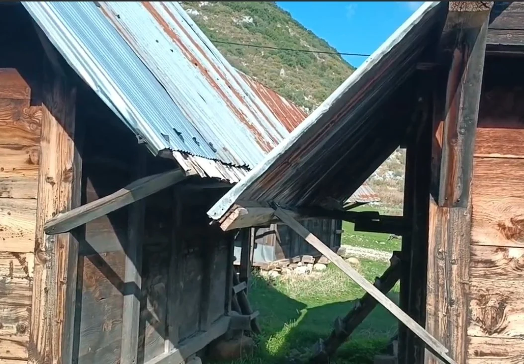 Ahşap ve metal çatıya sahip küçük bir ahşap ev, çatının bir kısmı çökmüş ve ahşap destekler devrilmiş.