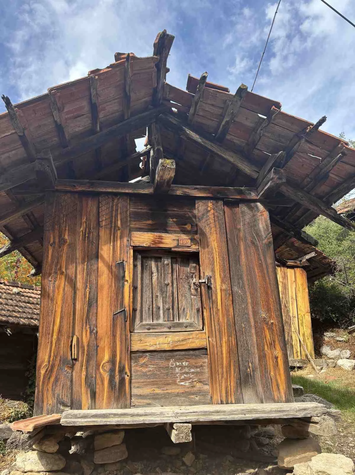 Ahşap, eski ve bakımsız bir ev, çatısı ve kapısı var, çevresinde doğal ortam.