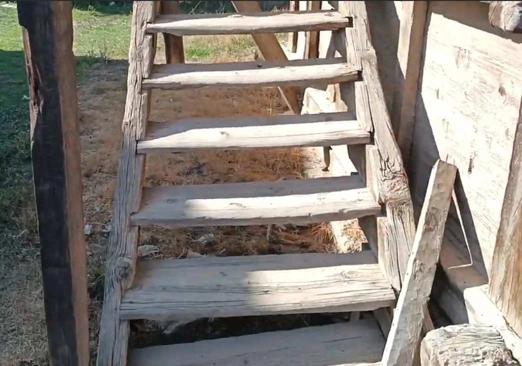 Ahşap merdiven, tahta yapısı ve çevresinde toprak ve çim alan.