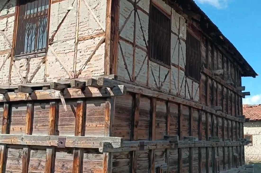 Ahşap ve taş malzemelerle inşa edilmiş, eski bir ev veya yapı. Çatı ve pencereleri olan geleneksel tarzda bir bina.