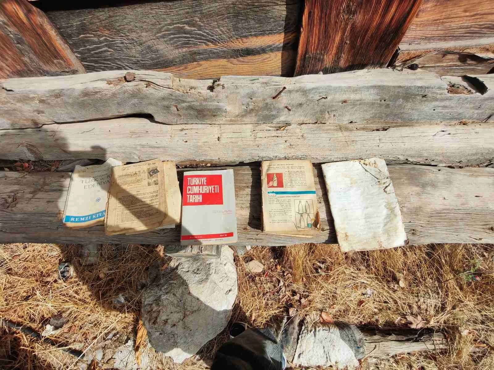 Dış mekanda, kuru otların üzerinde eski ve yıpranmış kitaplar ve dergiler bulunuyor.
