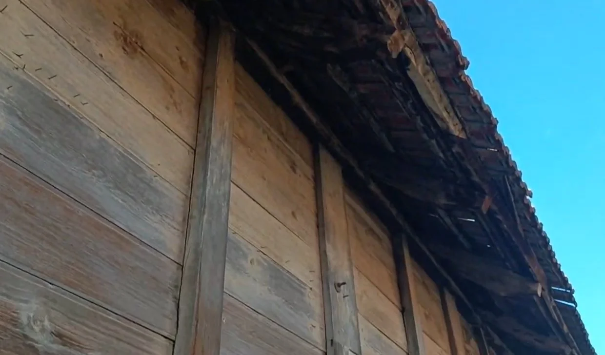 Ahşap evin dış cephesi, çatısı ve gölgesi görünmektedir.