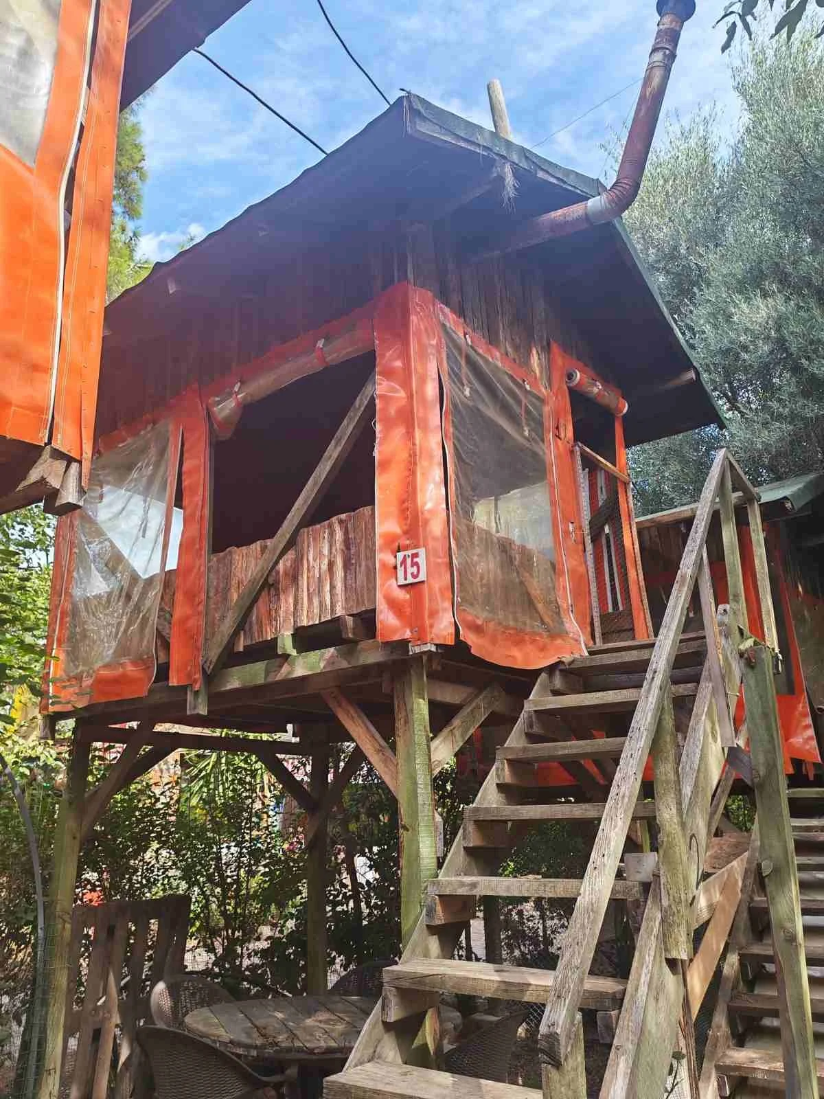 Ahşap bir kulübe veya kışla, üst kısımlarda su boruları ve denge çubukları bulunan, yükseltilmiş ve merdivenle çıkılan bir yapı.