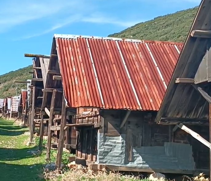 Ahşap ve metal çatılı eski kulübeler veya ahırlar sıralanmış.