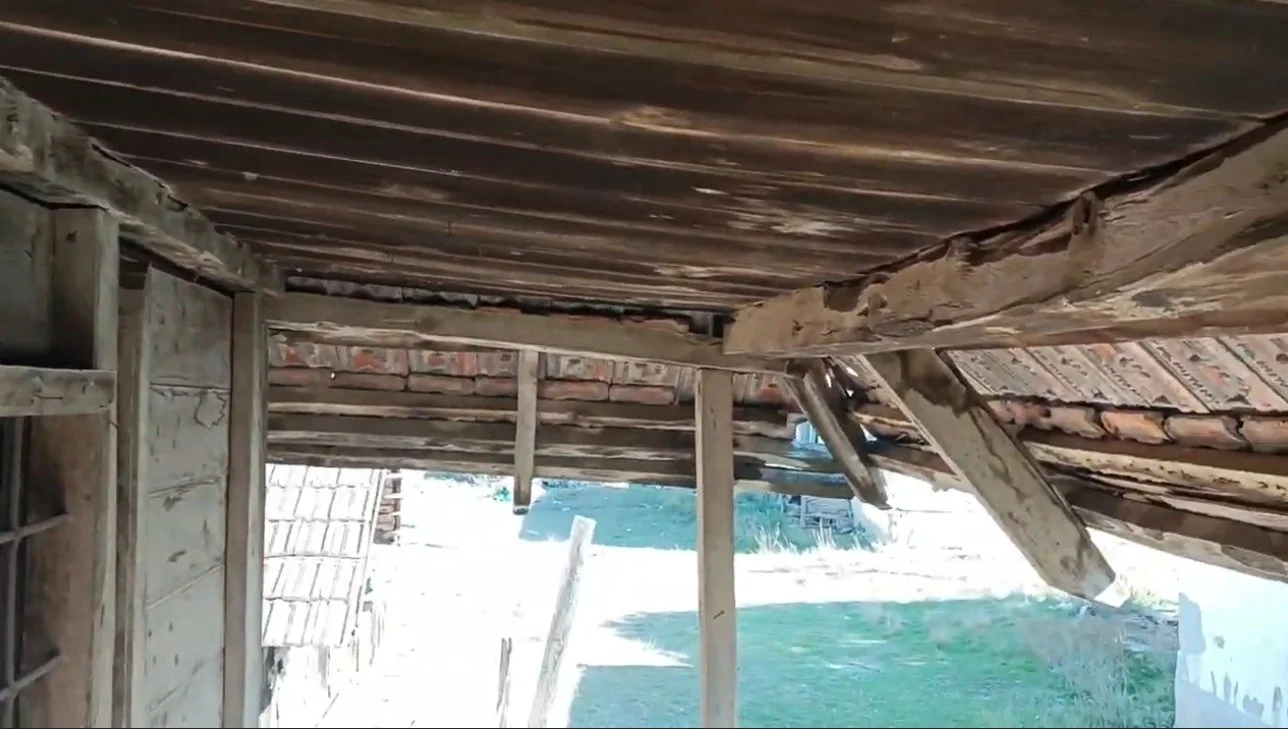 Ahşap bir çatının iç kısmı, bazı kısımlarda hasar ve kırıklar mevcut.