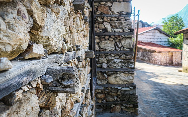 Taş duvar ve ahşap sopalarla yapılan sıva çalışması devam eden eski bina.
