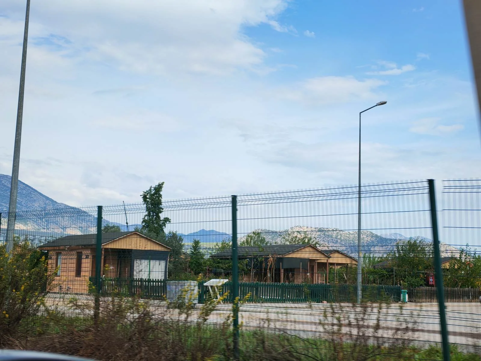 Dağlık bölgede, çitler ve küçük ahşap evler ile çevrili açık alan.