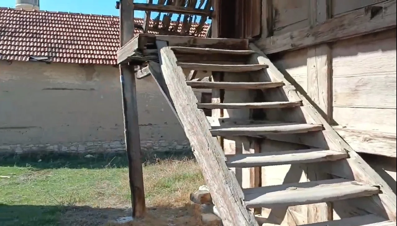 Ahşaptan yapılmış, eski ve yıkık merdiven, bir evin dış cephesine bitişik duruyor.