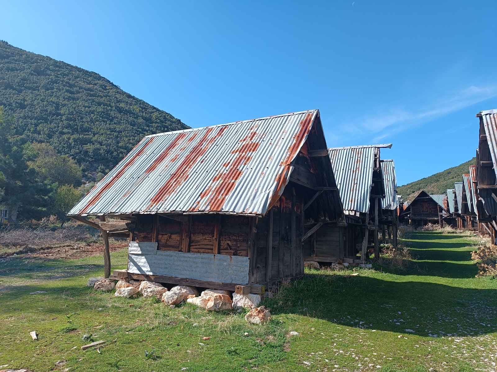 Dağ manzaralı alanda, eski ve rustik metal çatılı ahşap küçük evler.