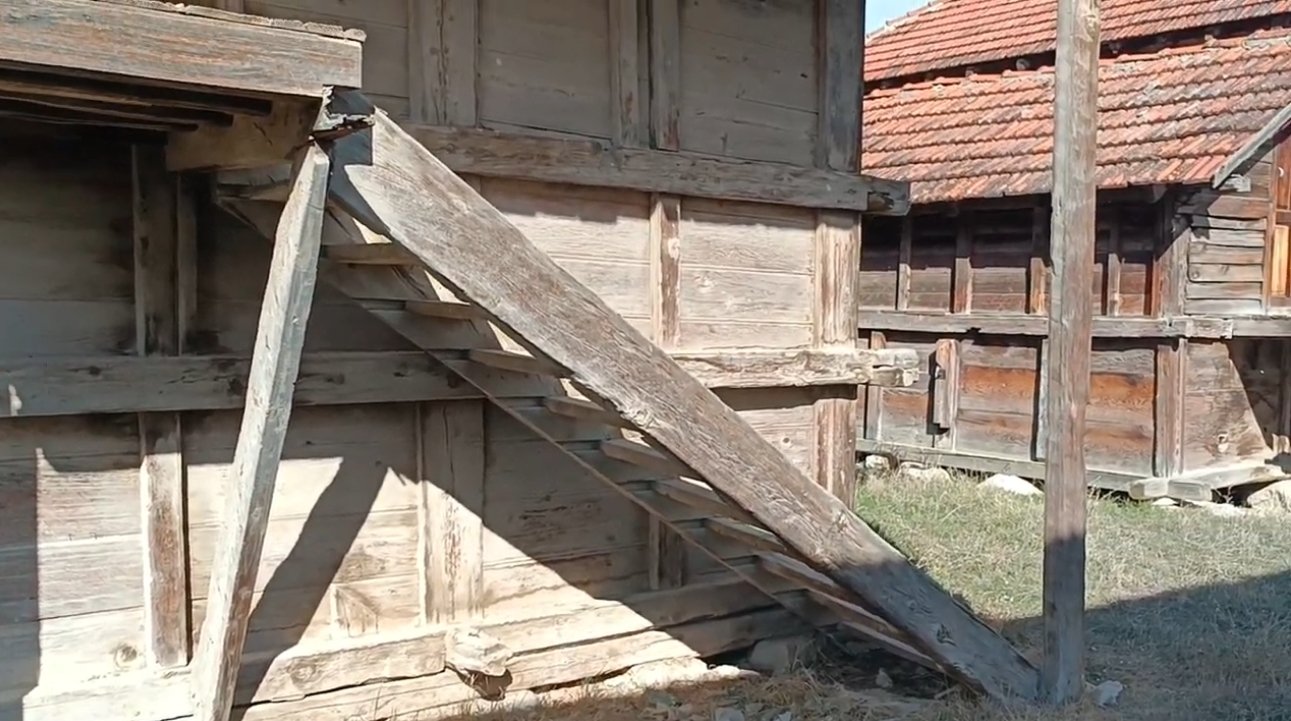 Ahşap merdiven ve eski ahşap binalar ile çatıları görülen köy evi veya ahşap yapı.